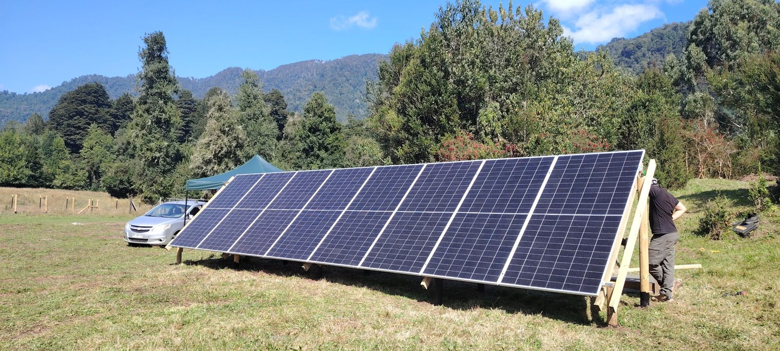 Paneles solares instalados en suelo, con cerros y bosque nativo de fondo
